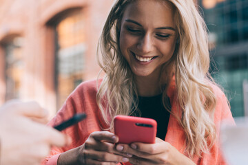 Cheerful caucasian blonde woman holding mobile phone sending and texting messages on leisure,20s...