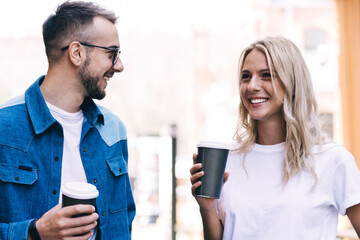 Funny caucasian male and female hipster friends talking to each other and joking on date walking on...