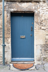 Blue wooden door on old cottage with stone wall.  Brass Letter box cover saying Letters on the front