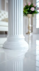 A white column with a vase of flowers in the background