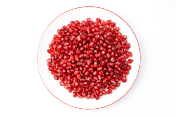 Gennevilliers, France - 01 02 2024: Close up of a white plate filled with red triangular pomegranate seeds on a white background.