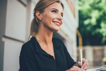 Happy female student with cute smile on face studying information notes learning at outdoors table...