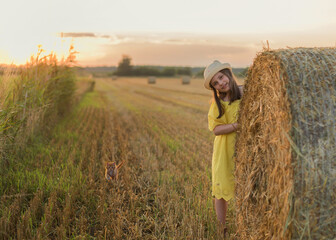 Beautiful 9-Year-Old Girl in a Yellow Dress in a Field Surrounded by Haystacks