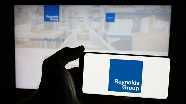 Stuttgart, Germany - 12-30-2024: Person holding mobile phone with logo of New Zealand packaging company Reynolds Group Ltd. on screen in front of web page. Focus on phone display.