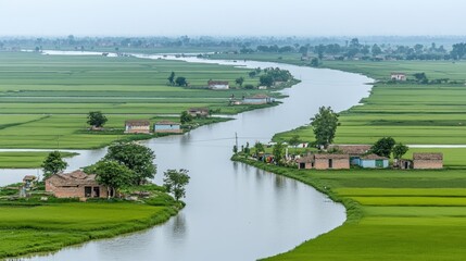 Obraz premium A serene landscape featuring a winding river through lush green fields and small villages.