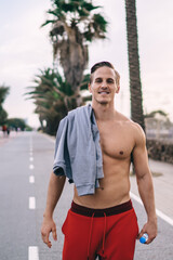 Half length portrait of successful sportsman with shirtless smiling at camera during workout time...