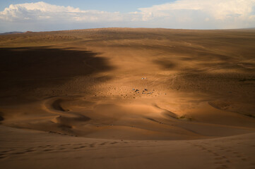 A stunning view of the Khongor Sand Dunes in the Gobi Desert, Mongolia, with dramatic light and shadows.