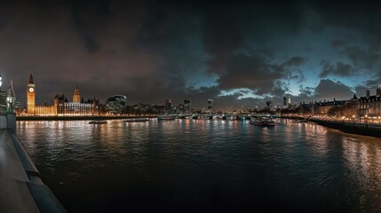 Fototapeta premium Panoramic view of the London cityscape at night, featuring the Houses of Parliament, River Thames, and illuminated buildings.