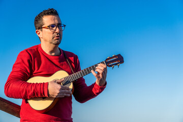 Obraz premium One man playing the ukulele, outdoors.