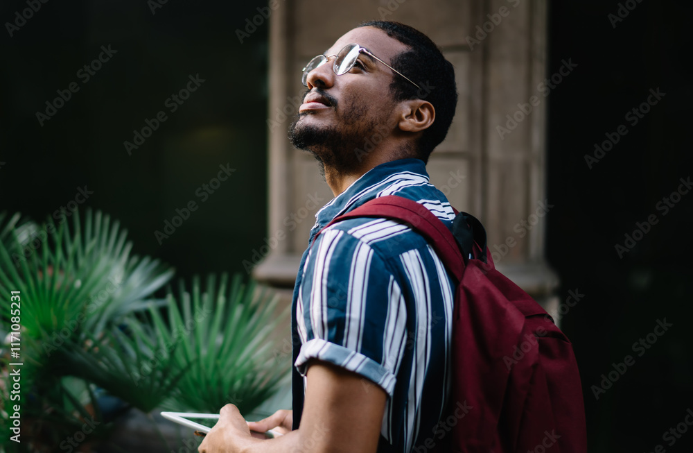 Poster positive dark skinned male traveler using digital tablet for searching location via navigation app w