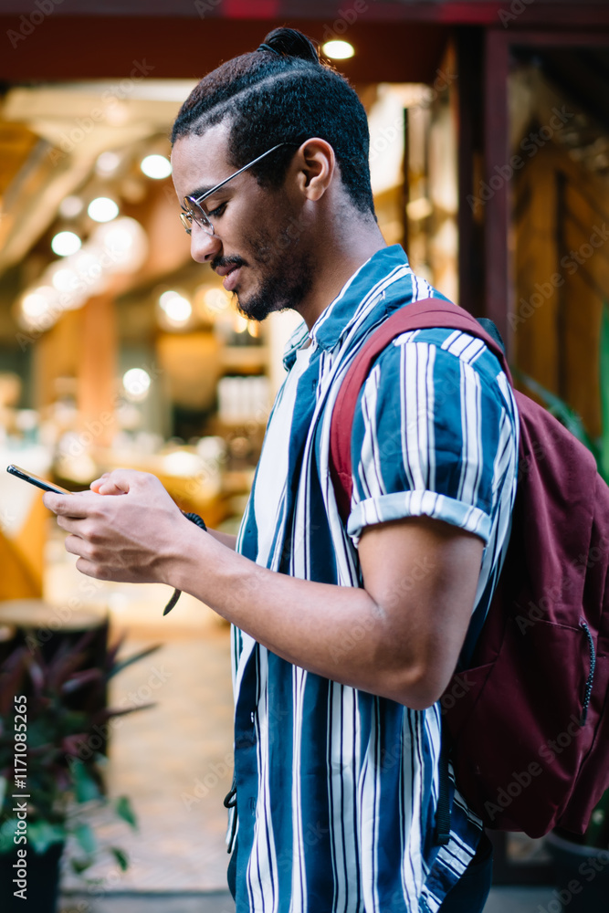 Poster smiling dark skinned male traveler walking with smartphone using navigation app searching destinatio