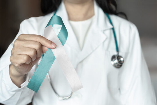 Teal and white ribbon for cervical cancer awareness month in January and HPV prevention with bow on medical doctor's hand support
