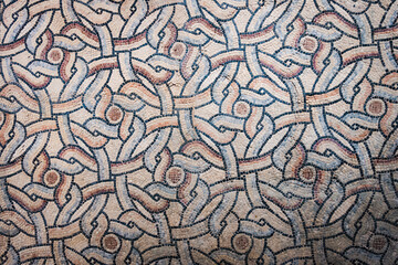 Geometric mosaic pattern in Ravenna with interlocking shapes and earthy tones, showcasing Byzantine art. Horizontal image.
