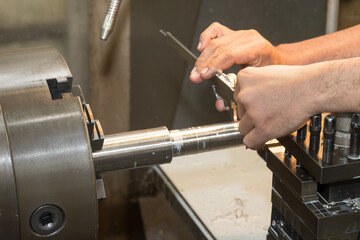 Close up scene the lath machine operator measuring dimension of turning parts by Vernier caliper.
