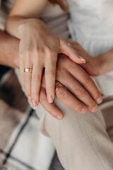 Close-up photo of hands of bride and groom in love during wedding ceremony against the backdrop of...
