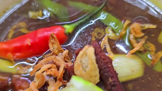 Rawon soup or Indonesian black beef soup, black color are from indonesian nut called kluwek. Served with lime, chili paste, salted egg, and tempe cracker