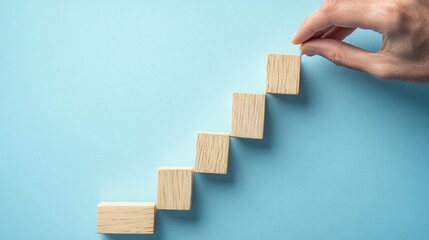 A hand adjusts wooden blocks arranged in a staircase pattern on a blue background.