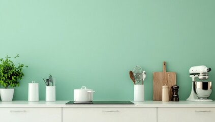 Minimalist kitchen countertop with appliances and utensils against a mint green wall.