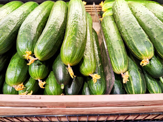 Fresh cucumbers arranged neatly in a wooden basket at a local market in mid-afternoon