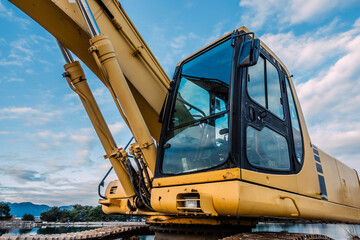 Detailed View of a Yellow Excavator Cabin on a Construction Site with Hydraulic Arms