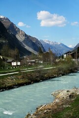 Fototapeta premium River flowing through a quaint village with mountains in the background. Zermatt, Switzerland