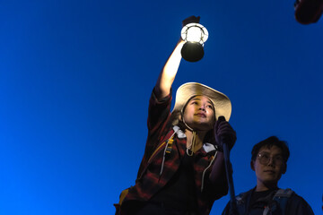Trekker woman holding camping lamp during hiking at night