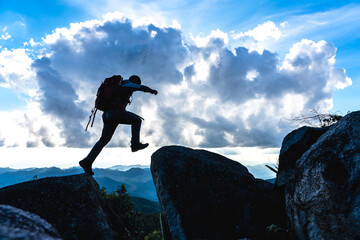 Silhouette mountaineer man jumping cross the rock to the peak
