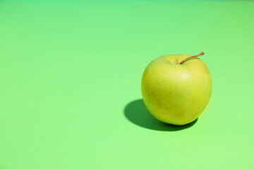 Fresh ripe apple on light green background, space for text