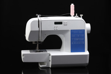 One sewing machine with spool of thread on black background