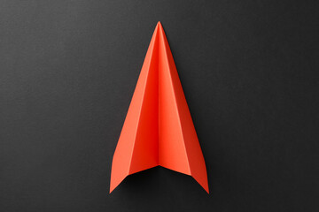 Fototapeta premium One handmade orange paper plane on grey background, top view