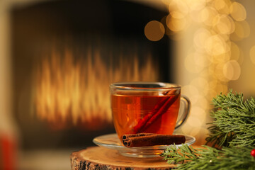 Cup of tea with cinnamon on table against blurred Christmas lights, bokeh effect. Space for text