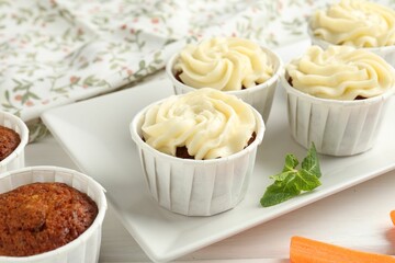 Tasty carrot muffins and mint on white wooden table, closeup