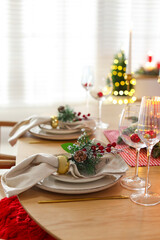 Christmas celebration. Festive table setting with dishware, glasses and decor in room