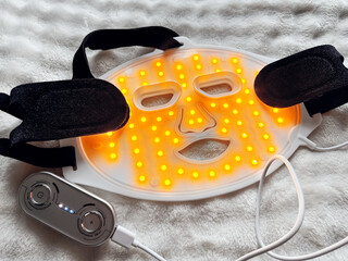 Led light therapy face mask on soft fabric, above view. Beauty treatment