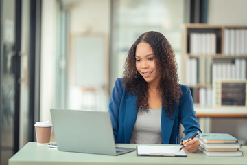 Fototapeta premium Female financial analyst working using a computer Surrounded by financial charts using digital tablet on table at home office and analyzing data documents