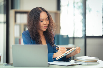 Female financial analyst working using a computer Surrounded by financial charts using digital tablet on table at home office and analyzing data documents