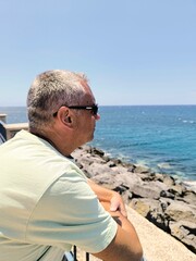 Young handsome man in profile looking at the sea from the pier.Boy with sunglasses, seen in...