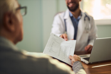 Close up of unrecognizable doctor  giving medical results to his senior patient.