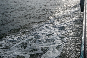 A serene and tranquil scene where gentle water waves create beautiful white foam under warm sunlight