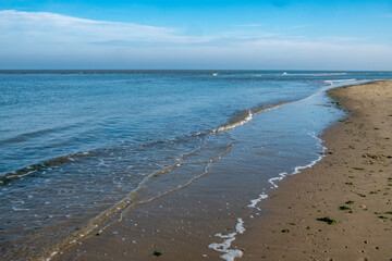 A picturesque and serene beach scene showcasing calm waters, gentle soft sand, and clear blue skies above