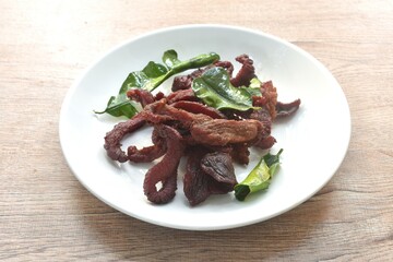 fried crispy salty fermenting beef meat with lemon leaf and chili on plate 