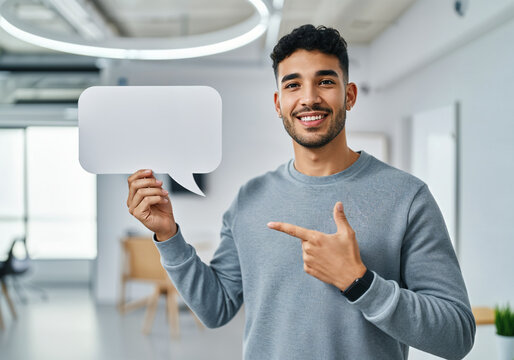 Hispanic worker holding empty speech bubble pointing at it promoting communication and feedback in office