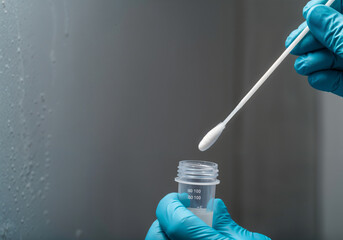 Gloved hands holding test tube and cotton swab, performing scientific experiment in laboratory setting