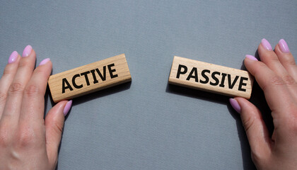 Active or Passive symbol. Concept word Active or Passive on wooden blocks. Businessman hand. Beautiful grey background. Business and Active or Passive concept. Copy space