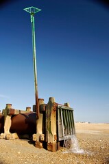 Sewage oulet on a gravel beach, with water coming out of the pipe.