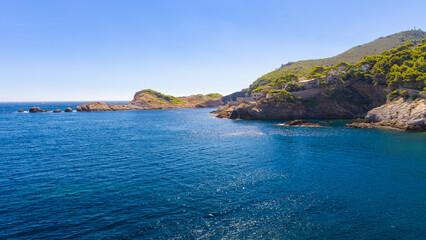 Fototapeta premium Punta de Plom con acantilados, casas entre pinos y mar azul brillante, Costa Brava, Cataluña, España.