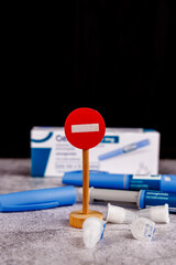 Diabetes control pens with semaglutide and wooden no-entry sign on a cement table