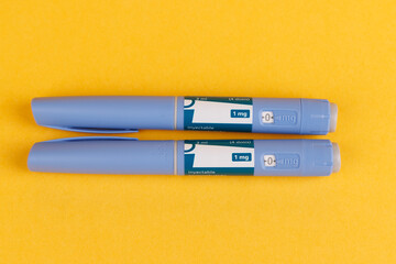 Glucose control medication pens with semaglutide on yellow background in top view