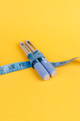 Semaglutide pens tied with tape on a yellow surface