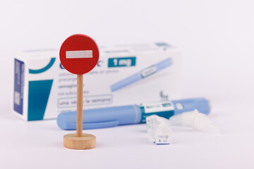Wooden stop sign and glucose control pen with semaglutide on a white background